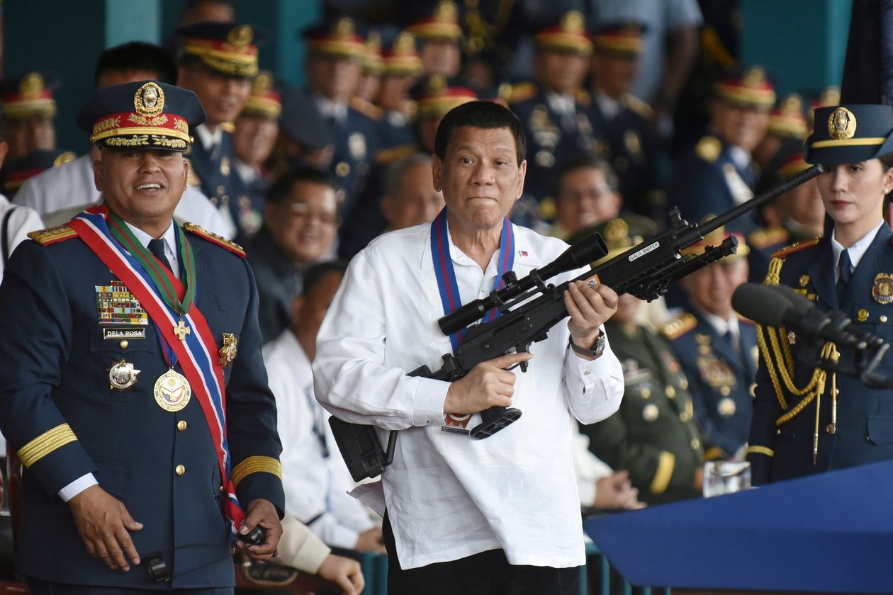 Philippine President Rodrigo Duterte holds a rifle next to outgoing Philippine National Police Chief Ronald Bato Dela Rosa.
(REUTERS/Dondi Tawatao)